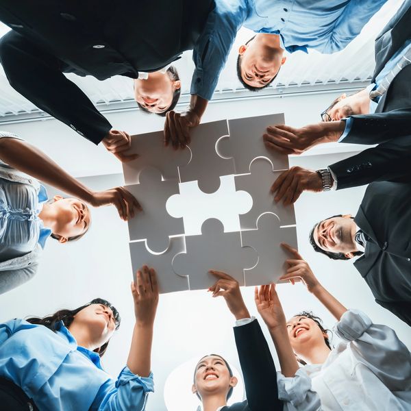 Team of businesspeople assembling puzzle pieces in a collaborative setting.