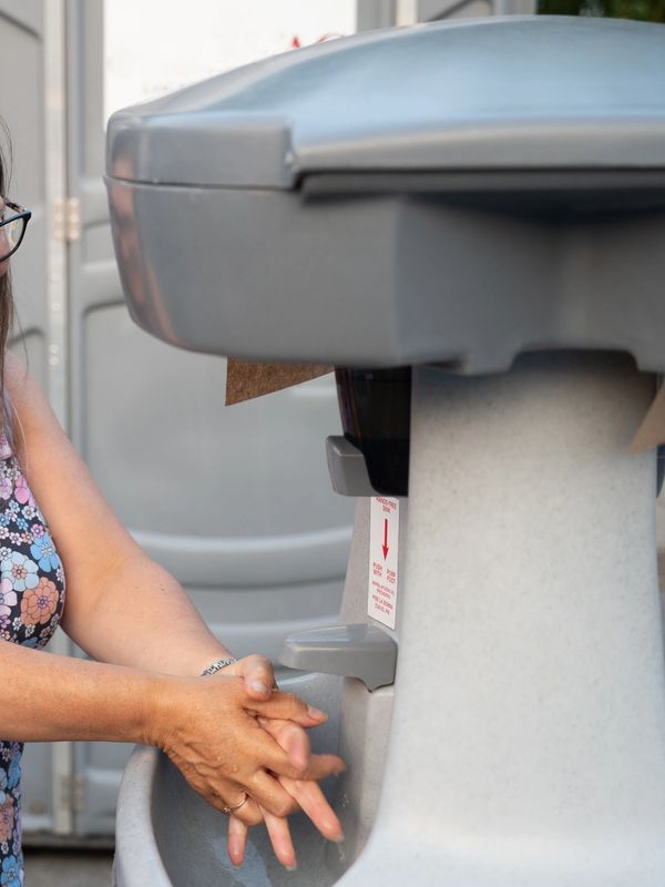 Person washing hands at an outdoor sink.