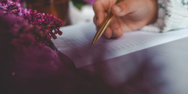 Hand writing with a pen on lined paper.