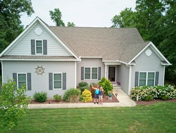 Single-story gray house with two people on the walkway.