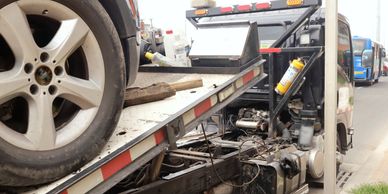 Car being towed on a flatbed truck on a city street.