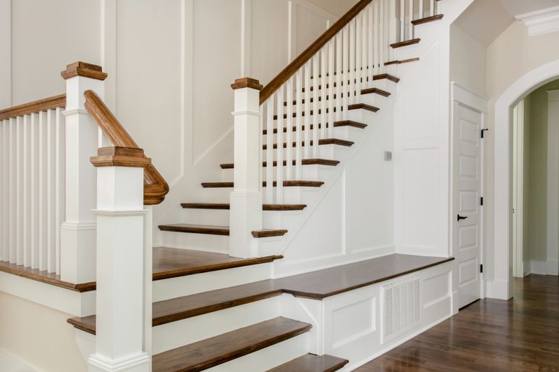 This image features a stylish and elegant staircase inside a modern home, complete with white railings and polished wooden steps. The sophisticated design and meticulous detailing of the staircase make it a focal point in the home's interior, expressing both luxury and contemporary style.