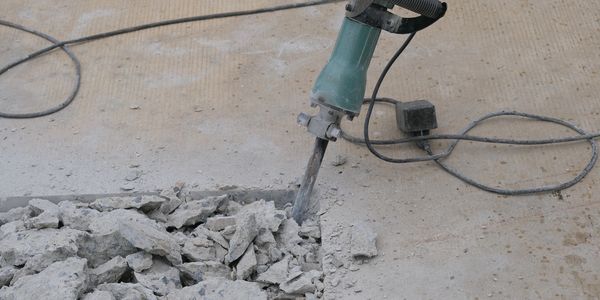 Electric jackhammer breaking concrete on a construction site.