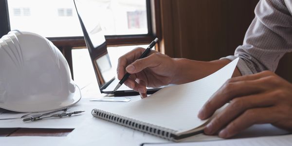 Project manager working at a desk with a pad in front of them and pencil in hand