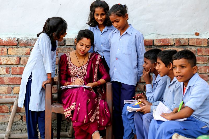 Confident village female teacher of Indian ethnicity explain information/ knowledge to the students in the class.