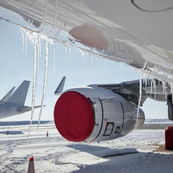Icicles hang from an airplane wing in a snowy airport.