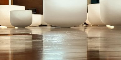 A collection of white ceramic bowls on a wooden floor with soft lighting.