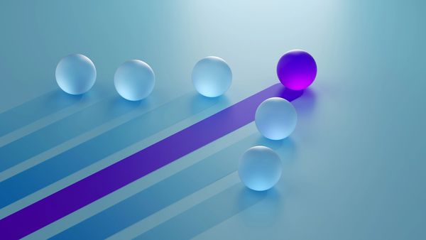 A distinct purple sphere leading a group of blue spheres against a light blue background.