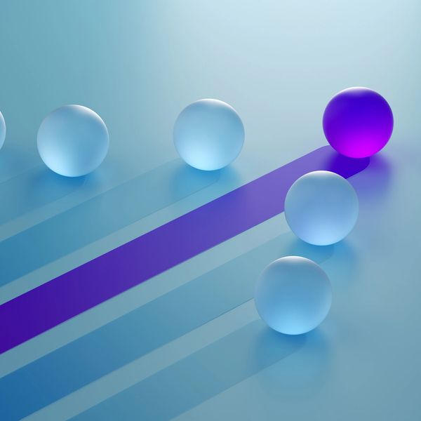A unique purple sphere stands out among many blue spheres.