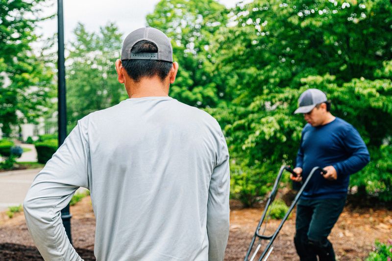 Professional Landscaper Hispanic Crew proudly working together to Plant a Flowerbed in a Public Neighborhood Park Median Green Space. Photo taken in Tennessee, USA (Southern USA)