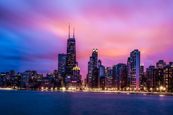 City skyline during vibrant sunset with water in foreground.