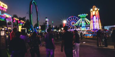 People walking at a vibrant night carnival with bright rides.