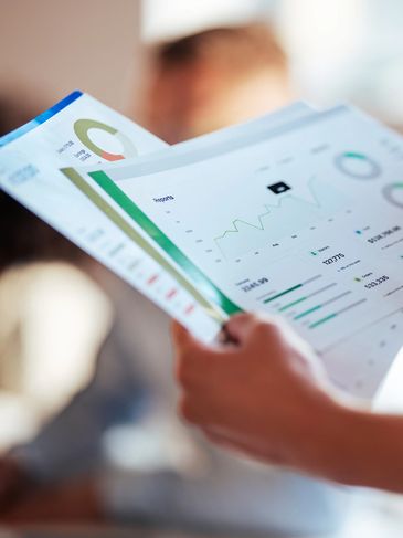 Person reviewing financial charts and graphs on printed documents.