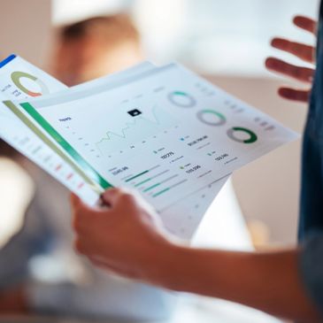 Person holding printed business reports with charts and graphs.