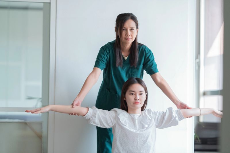 patient appointment with professional asian physiotherapist in clinic massaging