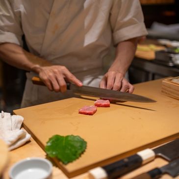 Chef slicing raw fish on a cutting board.