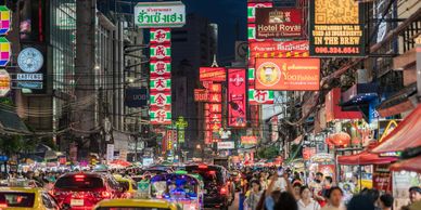 Busy city street at night filled with neon signs and heavy traffic.