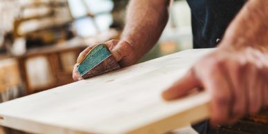 A person sanding a wooden board.