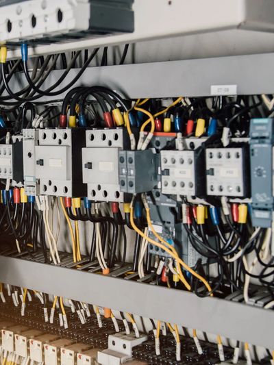 Technician wearing gloves working on electrical control panel wiring.
