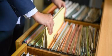The image is of a filing cabinet with an attorney's hand suggesting attorney assisted patent filings