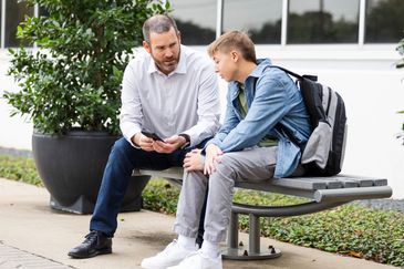 Teenage boy talking to his parents outdoors in a park.