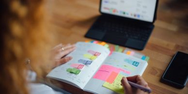 Person organizing schedule with colorful sticky notes and digital tablet nearby.