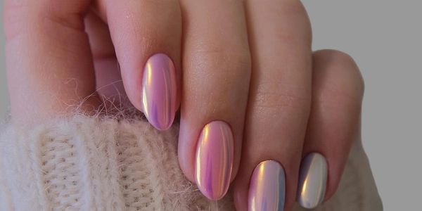 Hand with iridescent pink and silver nails wearing a knitted sweater.