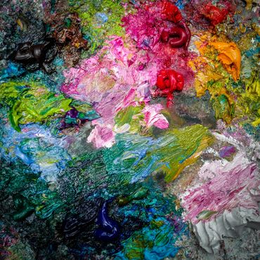 Colorful oil paint blobs on a palette.