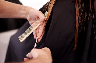A person getting a haircut with scissors and a comb.