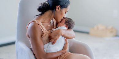Mother lovingly holding and kissing her newborn baby.