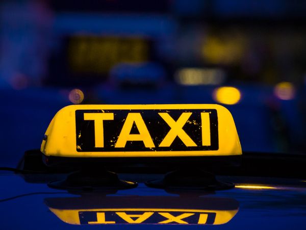 Illuminated taxi sign on a car roof at night.