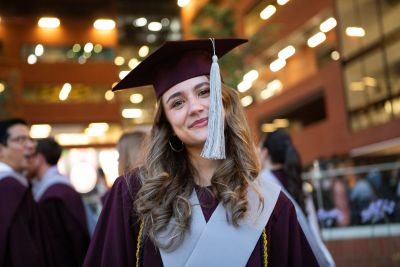 Smiling female graduate in cap and gown.