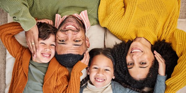 Happy family lying down together, smiling warmly at the camera.