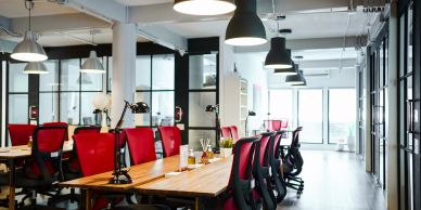 Modern office space with red chairs and pendant lights.