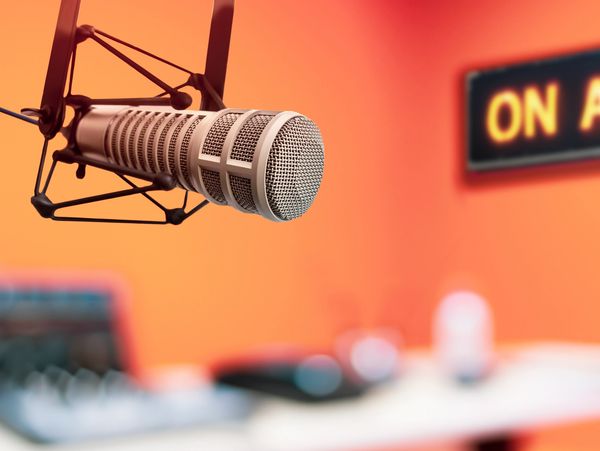 Professional microphone in a radio studio with an 'On Air' sign.