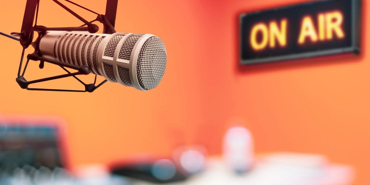 Close-up of a microphone with an 'On Air' sign.