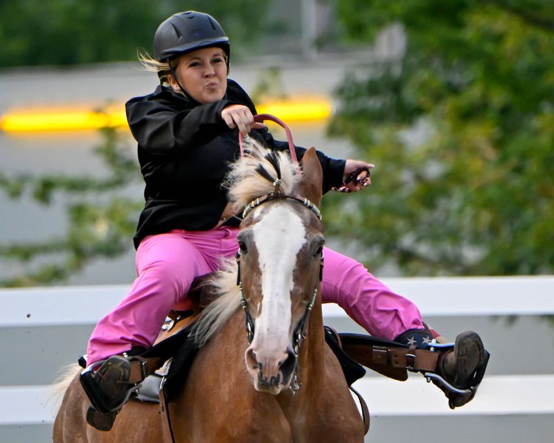 A teenage girl bouncing up and down in the saddle as she and her horse make the run to the finish line during the Barrel Race at the 4H Fair