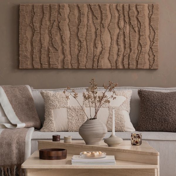 living room interior with textured wall art, sofa, pillows, wood coffee table, minimal decor