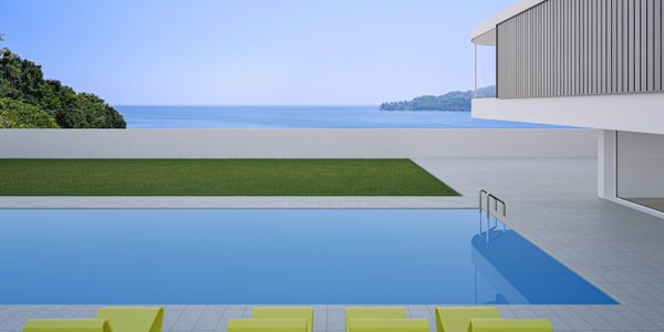 Modern poolside with sleek yellow loungers overlooking the ocean.