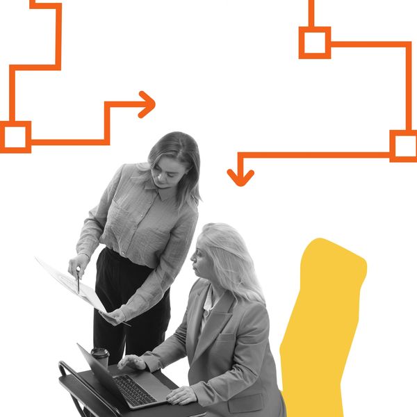 Two women working collaboratively with flowchart graphics above them.