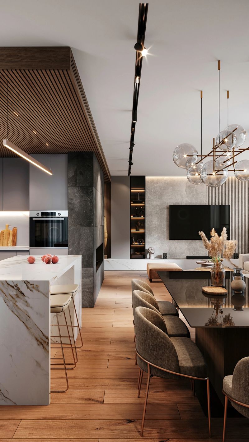 Modern apartment kitchen interior with kitchen island, kitchen supplies, , oven and dining table with chairs and pendant lamp above. Living room  with  TV screen on the concrete wall in the background. White and wooden paneling ceiling, concrete wall and parquet. Render.