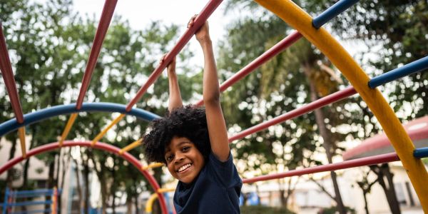 Smiling child playing on colorful jungle gym outdoors.