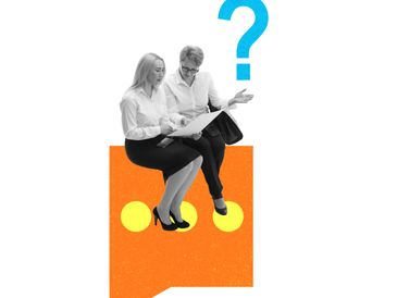 Two businesspeople sit on a large question mark, discussing documents.
