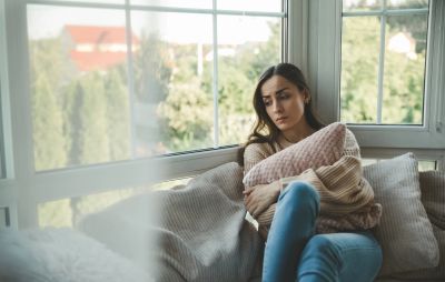 Woman looking sad and lonely by the window.