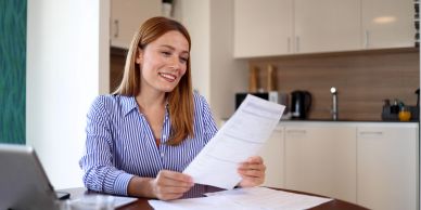 Woman smiling reading a document at home.