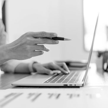Person pointing at a laptop screen while typing.