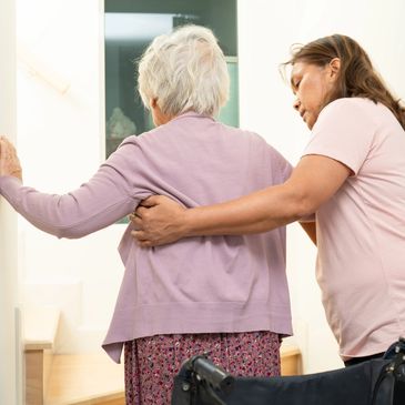 Caregiver assists elderly woman with walking, providing support.