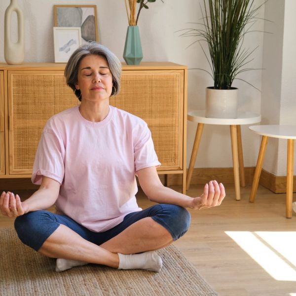 Senior woman meditating peacefully at home.