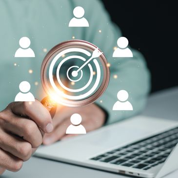 Hand holding magnifying glass focusing on a target surrounded by user icons.