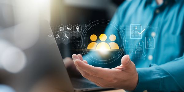 Hand presenting digital teamwork and HR icons over laptop.